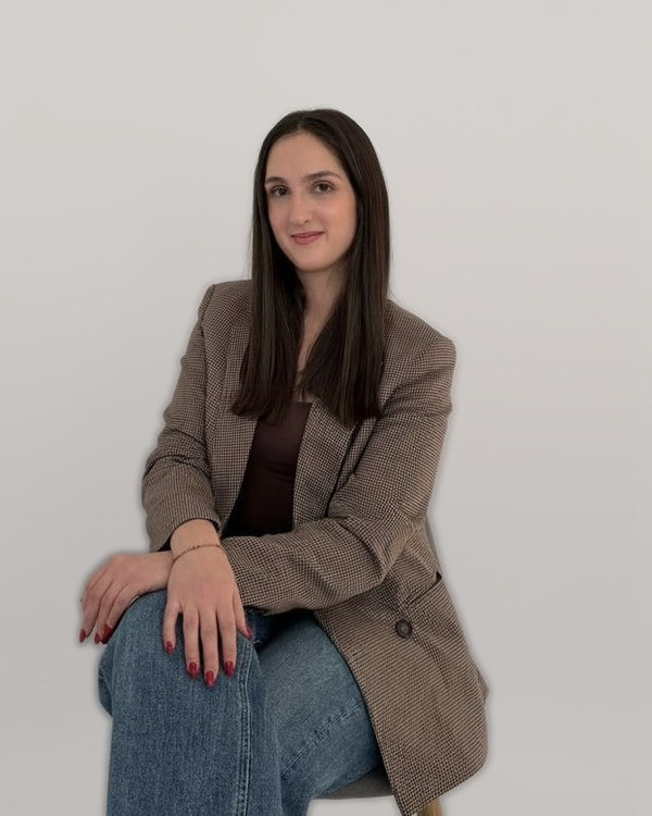 Tatiana Poupinha, seated, wearing a checked blazer.